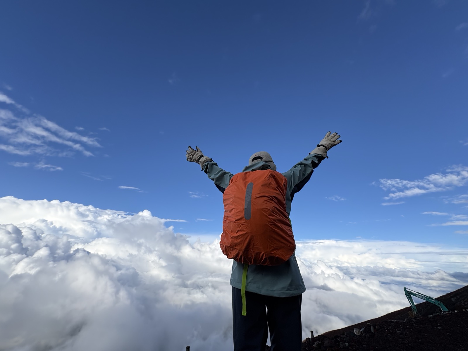 富士山登山ツアーで山頂付近の雲海を前に万歳する様子
