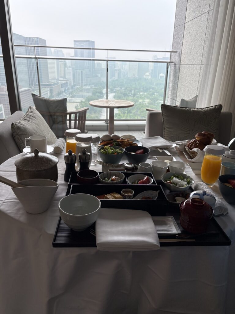 客室のテーブルに並んだ朝食とバルコニー越しの景色